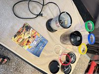 All components laid out: motor base, cups with colored rings, blades, lids, booklet