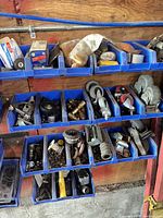 Blue bin shelves containing casters, brass fittings, fasteners, abrasive pad, brackets