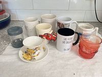 Group shot of all items: six mugs, teacup & saucer, red glass, plastic timer