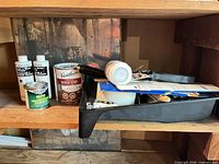 All items on shelf including stain, glow paint, primers, tray, roller, tape, hardware