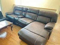 Full view of brown faux leather sectional with right arm chaise and console