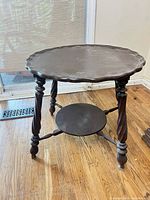 Full view of round wooden side table, showing top surface, legs, and lower shelf