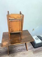 Side table supporting inverted smoking stand showing cabinet and tall handles