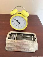 Yellow Miniso alarm clock beside open Rolls Razor case