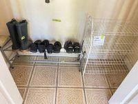 Overall view of boots, four pairs of shoes on metal shoe rack, and adjacent wire shelving unit