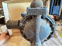 Side view of Sandpiper AODD pump showing diaphragm housing and threaded port with corrosion