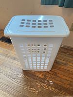 Tall white plastic hamper with lid closed showing square ventilation holes