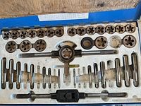 Interior of blue tap and die set showing taps, dies and handles