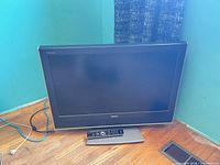 Full view of Toshiba REGZA 32-inch TV on stand with remote and power cable visible