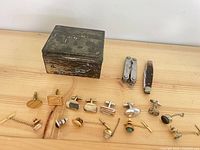 Group shot of box, multitool, pocket knife, cufflinks and tie accessories