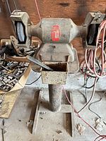 Full view of bench grinder mounted on pedestal with both wheels visible