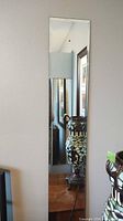 Mirror 1 mounted on wall, showing slim rectangular shape and beveled edge