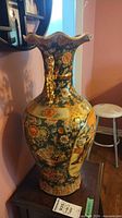 Full view of vase showing overall form, floral pattern, gilt handles and scalloped rim
