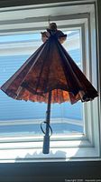 Folded brown paper parasol hanging in window