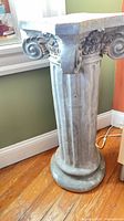 Full view of gray Ionic pedestal, showing capital and base