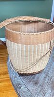 Front view of large handwoven wicker shoulder basket showing strap and two-tone weave
