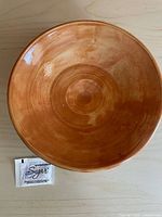 Top view of orange glazed terracotta bowl beside sugar packet for scale