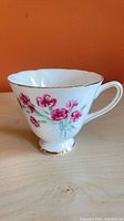Side view of teacup showing pink floral pattern and gold trim