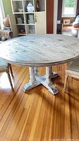 Overall view of round whitewashed solid wood dining table with two upholstered chairs