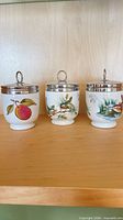 Front view of all three porcelain canisters showing motifs and lids