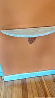 Front view of semicircular marble-top wall shelf mounted on wall