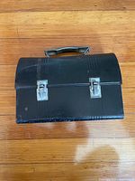 Closed black metal toolbox front view showing latches and handle