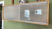 Front view of wall-mounted maple veneer cabinet with frosted glass sliding doors