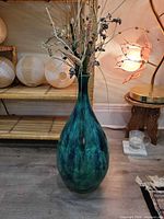 Full view of tall teal glazed ceramic floor vase with dried stems for scale