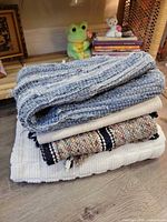 Stack of four folded rugs showing differing weaves and colours