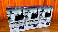 Front view of three retail boxes of champagne flutes