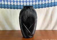 Full front view of black ribbed milk glass vase