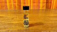 Full view of vial standing on tabletop showing label and flakes