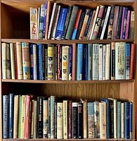Full view of three shelves densely filled with hardcover and paperback books