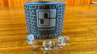 Three crystal duck figurines displayed in front of Swarovski tube container