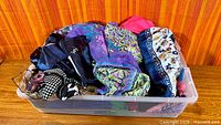 Full view of storage bin filled with assorted scarves