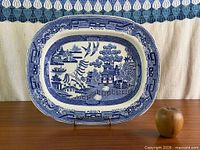 Front view of Blue Willow platter on stand with apple for scale
