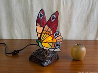 Lamp unlit beside apple for scale, showing full piece and cord