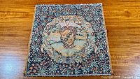 Full view of square Belgian jacquard coat of arms tapestry on wooden surface