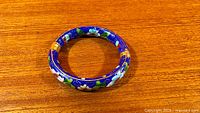 Top view of blue cloisonné floral bangle on wood surface