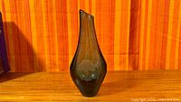 Full view of blue glass bud vase on wood surface