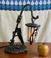 Full view of frog lamp with lantern lit, apple for scale