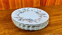 Stack of five Brigadoon side plates showing pattern and gold rim