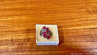 Ring top view in box showing ruby cluster and topaz accents