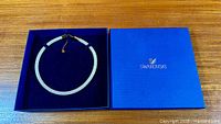 Necklace laid in open Swarovski blue box
