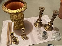 Group shot of brass urn, four candlesticks, packaged beeswax candles, two bubble-wrapped drip cups