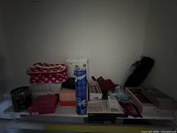 Shelf with assorted boxed beauty items, wax bead jar, aerosol can, makeup palette and bags