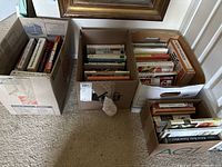 Four boxes filled with assorted books on floor