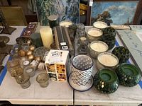 Wide view of assorted candles, jar candles, pillar candles, mosaic and ribbed glass holders on table