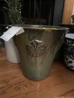 Large metal planter with medallion, adjacent ceramic pots visible
