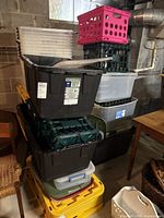 Stack of assorted plastic totes, milk crates and loose lids